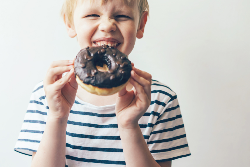 Young boy with chocolate frosted donut on white background