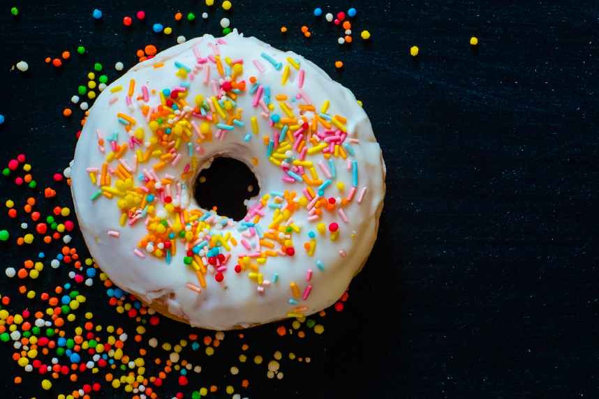 Donut with white frosting and colorful sprinkles on black background