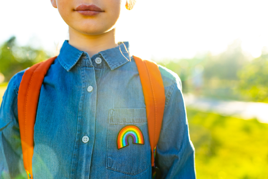 Young child with rainbow patch on shirt, outside on a sunny day