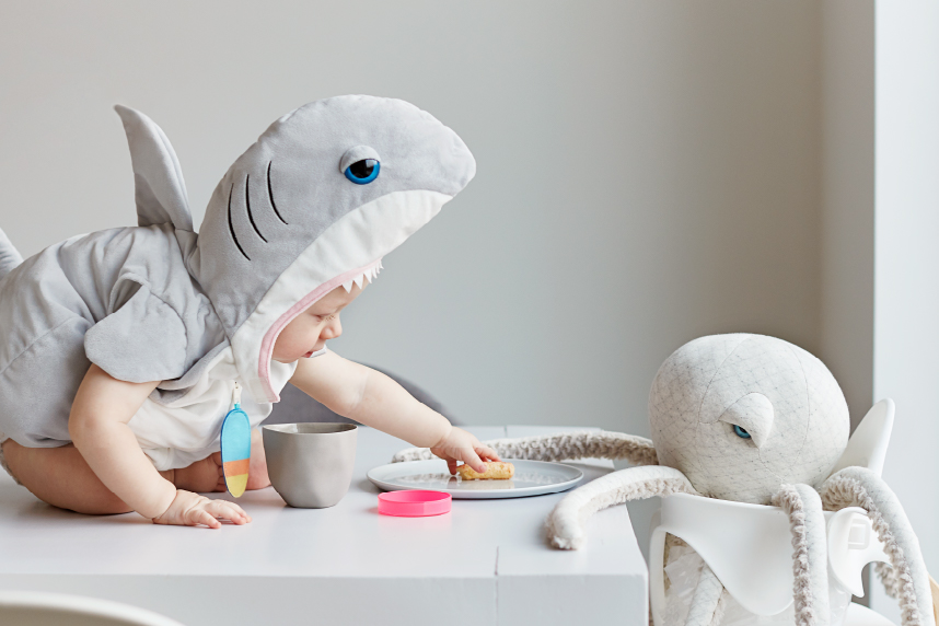 Infant dressed as shark with toy octopus