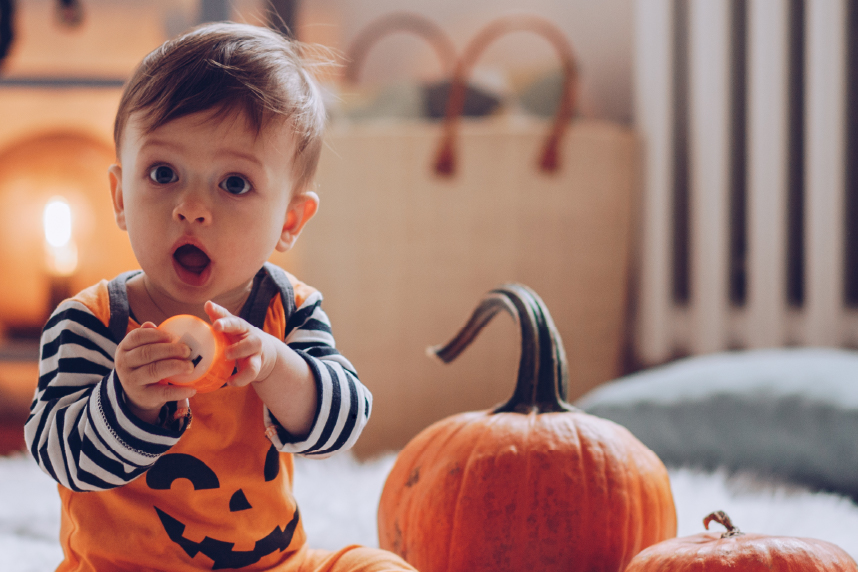 Toddler dressed as jack-o-lantern with pumpkins