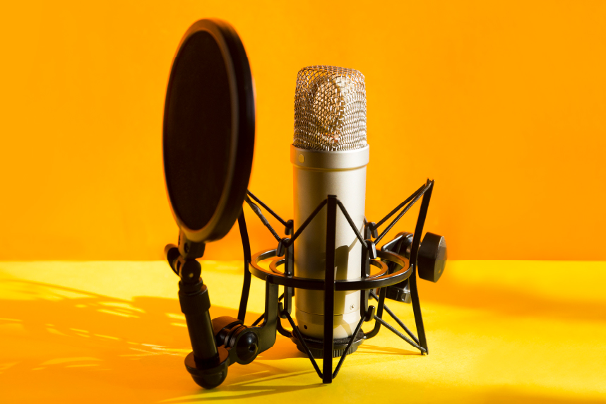 Podcasting microphone with pop filter on orange background