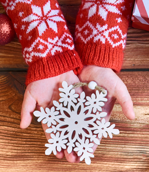 Child's hands holding snowflake ornament