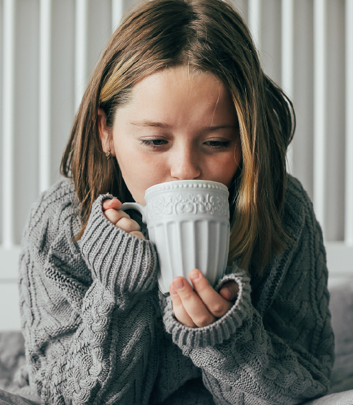 Young girl in grey sweater drinking from a large cup