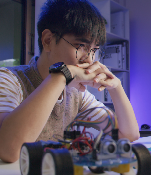 Young man with hand-build robot in foreground