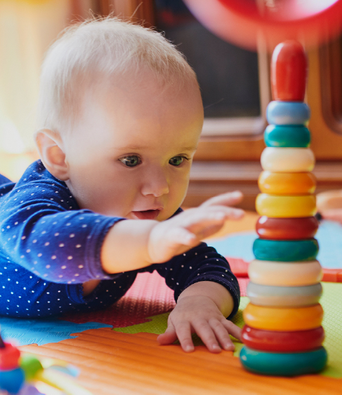 Infant reaching for colorful stack of rings