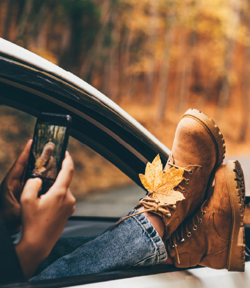 Person photographing an autumn leaf on their boots
