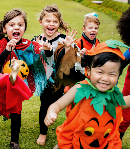 Children running outside while wearing various Halloween costumes