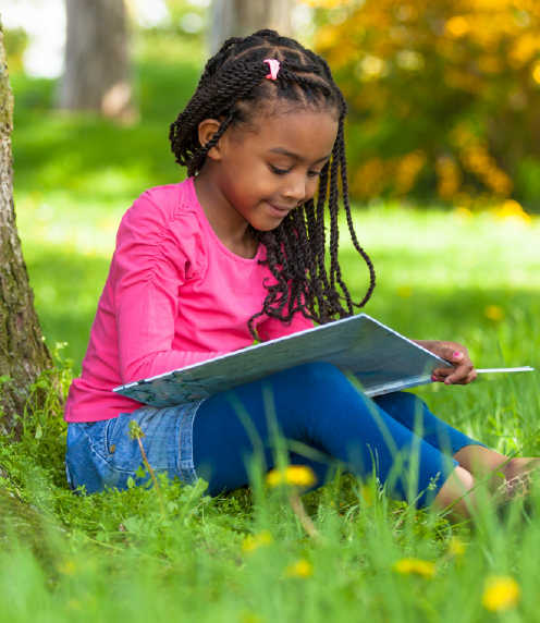 Little girl reading outside