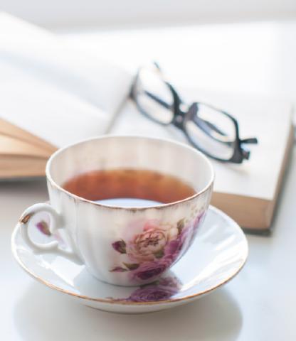 English tea cup, open book, and glasses