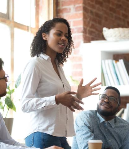 African American woman speaking to a group of colleagues 