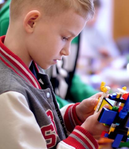 Young boy looking at plastic construction block creation