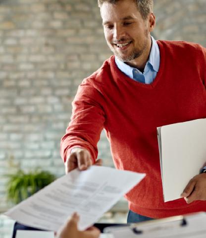 Man handing his resume to a figure out of camera