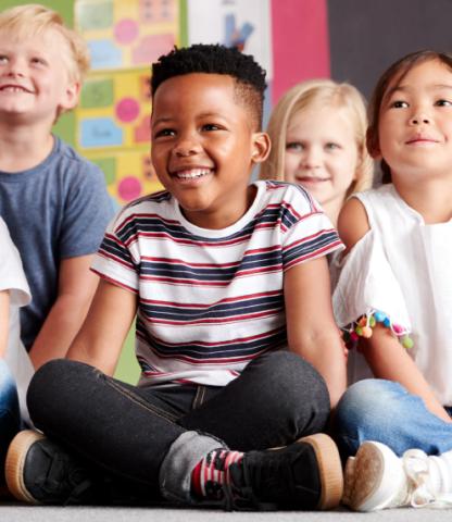 A group of happy, diverse children sitting ont he floor