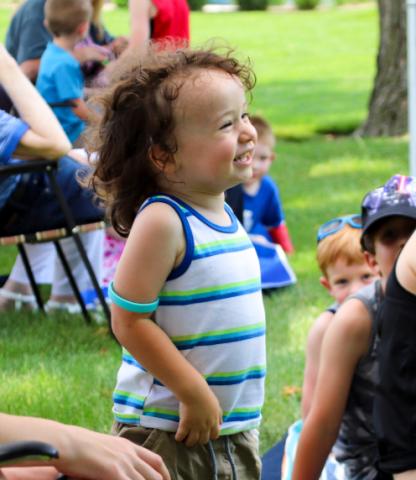 Happy young boy standing outside in a group of people