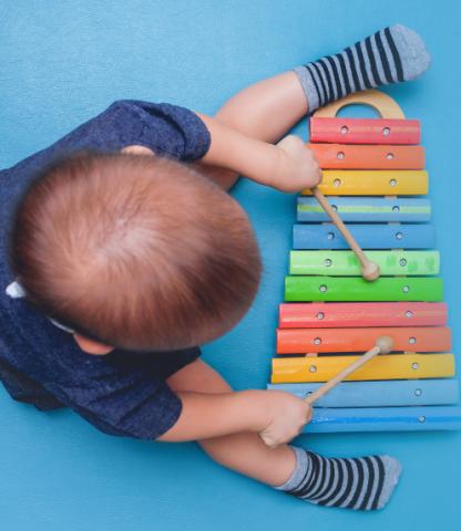 Overhead photo of infant boy playing with xylophone