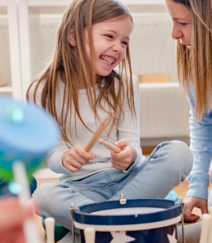 Little Girl Playing Drum with Mother