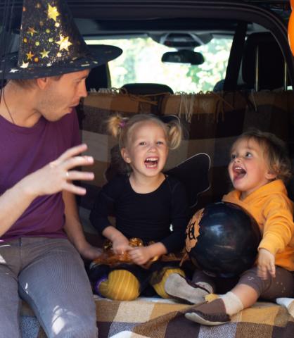 Parent and children sitting in the back of an SUV decorated for Halloween