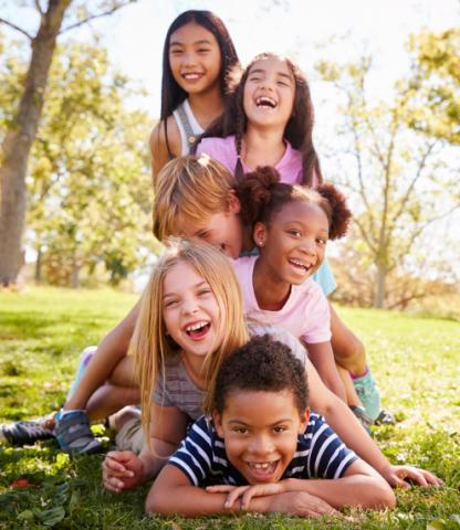 Pile of happy children laying on the ground outside