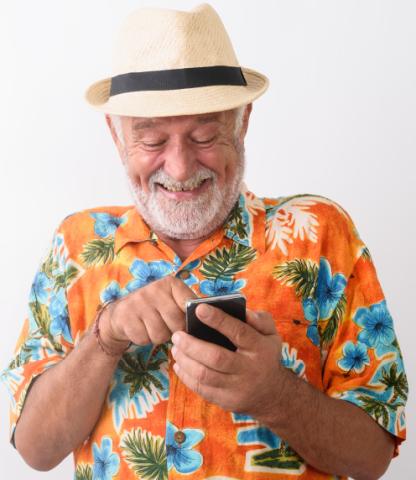 Senior man in Hawaiian shirt and Panama hat using his smartphone