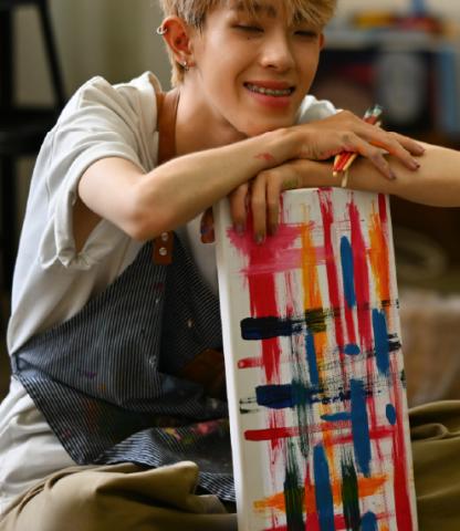 Smiling teenage artist leaning on painting