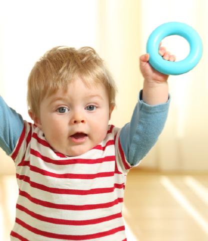 Infant holding up round rattle toy 