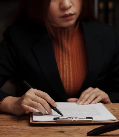 Young woman in business suit reviewing paperwork on a clipboard