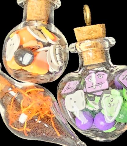 Three small glass bottles filled with Halloween-themed trinkets