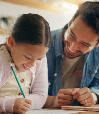 A teacher watching a student write on a paper