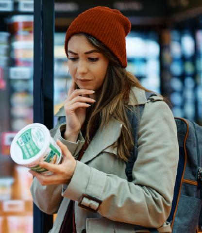 Young woman examining the back of a package in a grocery store