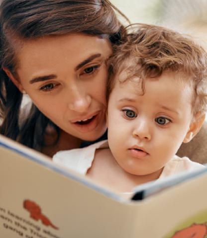 Intrigued little boy looking at a book with his mother