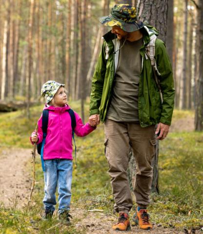 Image: Father and daughter smiling while looking at each other while on a hike through the woods..