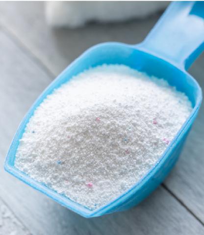 A blue scoop filled with white, powdery laundry detergent