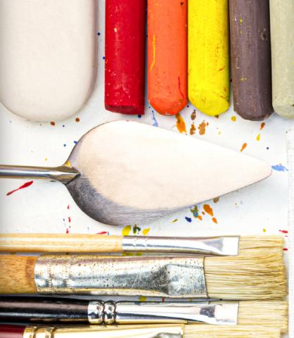 An eraser, five chalk pastels, a palette knife, and three paint brushes