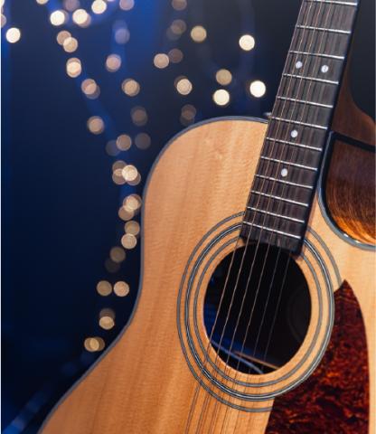 Acoustic guitar on dark blue background with fairy lights