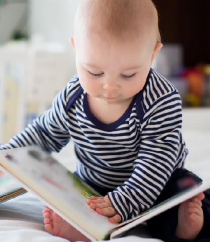 Infant in blue striped top looking at a book