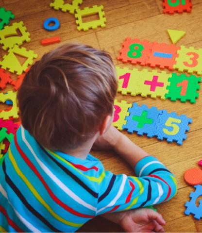 Young boy playing on floor with foam interlocking numbers