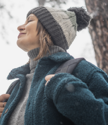 Woman out in the woods while dressed in winter coat and hat