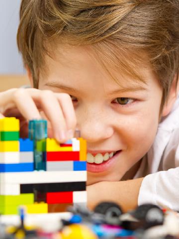 Close up of smiling young boy building with Lego plastic bricks