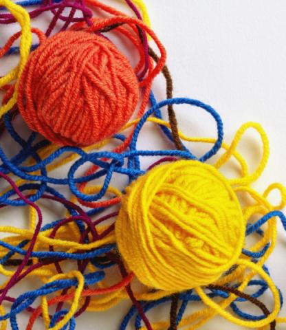 Two balls of yard surrounded by unraveled threads