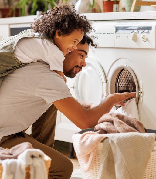 Father and daughter removing clothes from a dryer