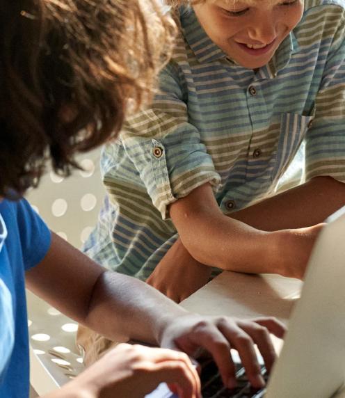 Boy pointing at laptop while his partner types