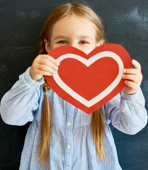 Young girl holding up hand-made paper heart