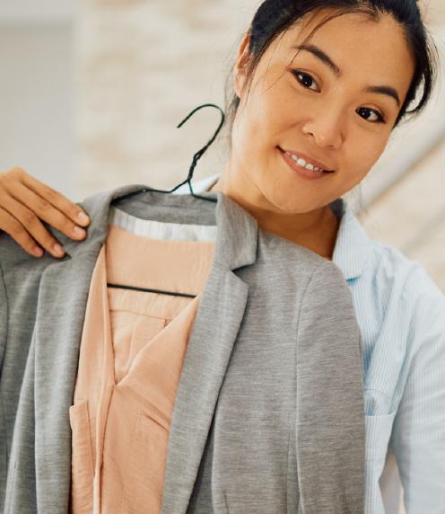 Young woman holding up suit jacket with shirt in front of her