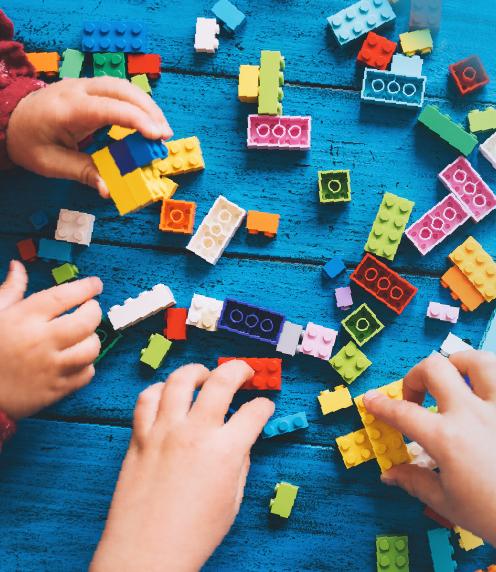 Two pairs of children's hands playing with Lego blocks