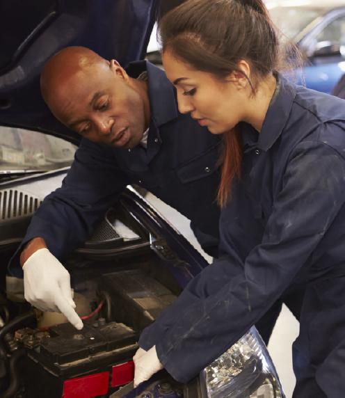 Young woman receiving instruction on how to repair a car