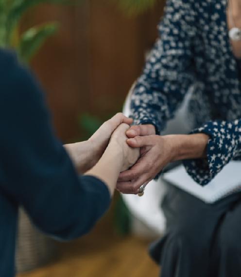 Woman holding another woman's hands in a comforting gesture