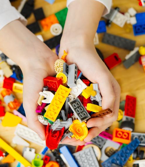 Teenager's hands holding up a pile of plastic bricks