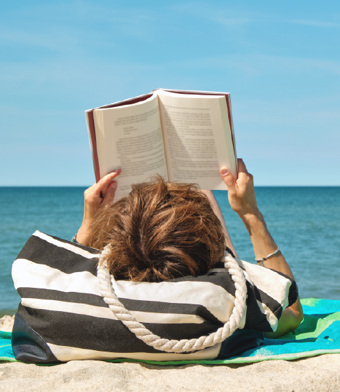 Woman laying on a beach reading