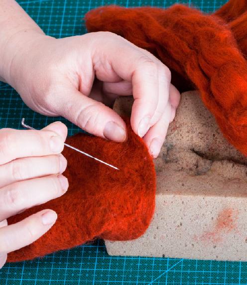 Close-up of hands working with a felting needle and wool